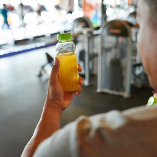Bottle of energy drink in hands of gym visitor